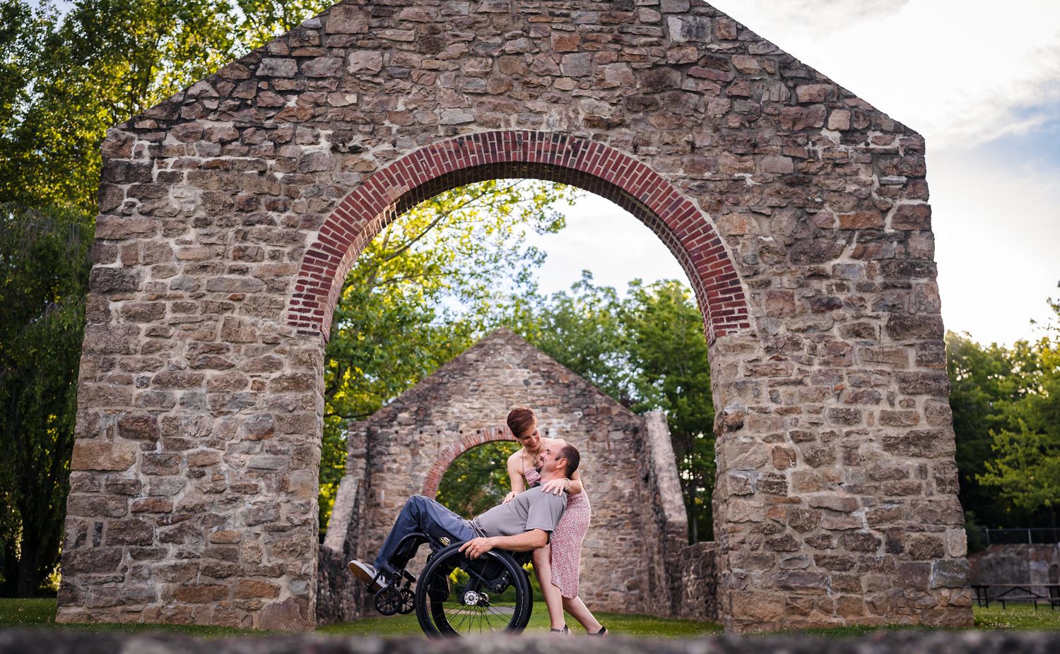 Stone archway frames romantic couple during outdoor photo session.