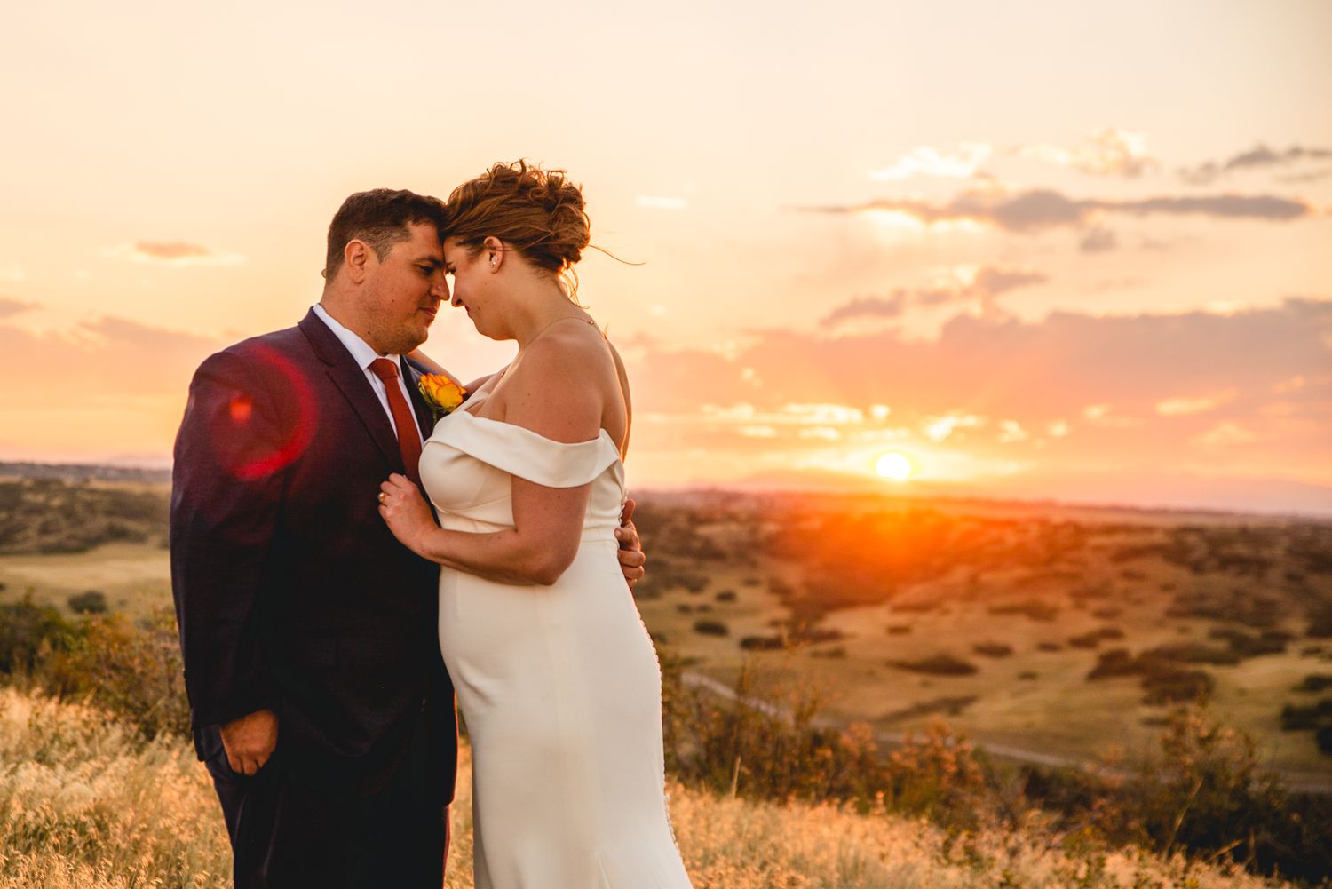 A romantic sunset wedding portrait set against a golden desert landscape.