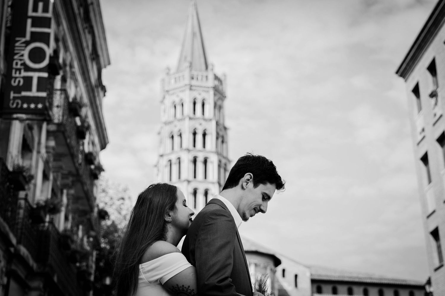 A romantic black and white portrait with a Gothic church spire in the background.