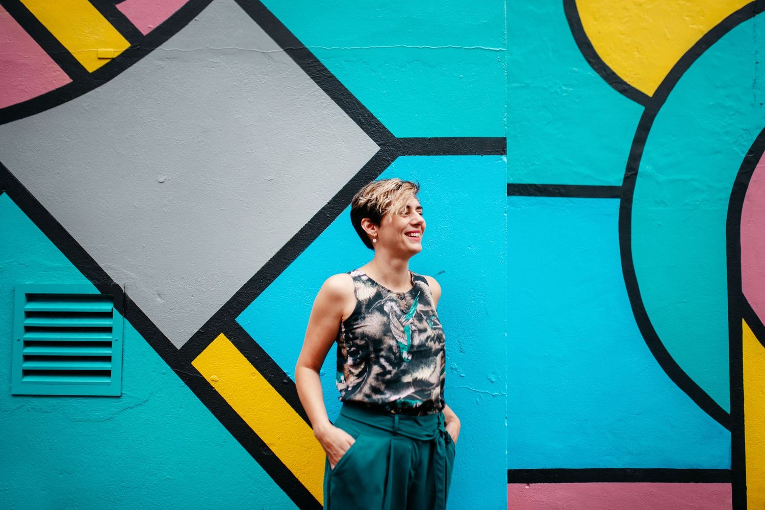 Colorful geometric mural with bright turquoise and yellow shapes on urban wall.