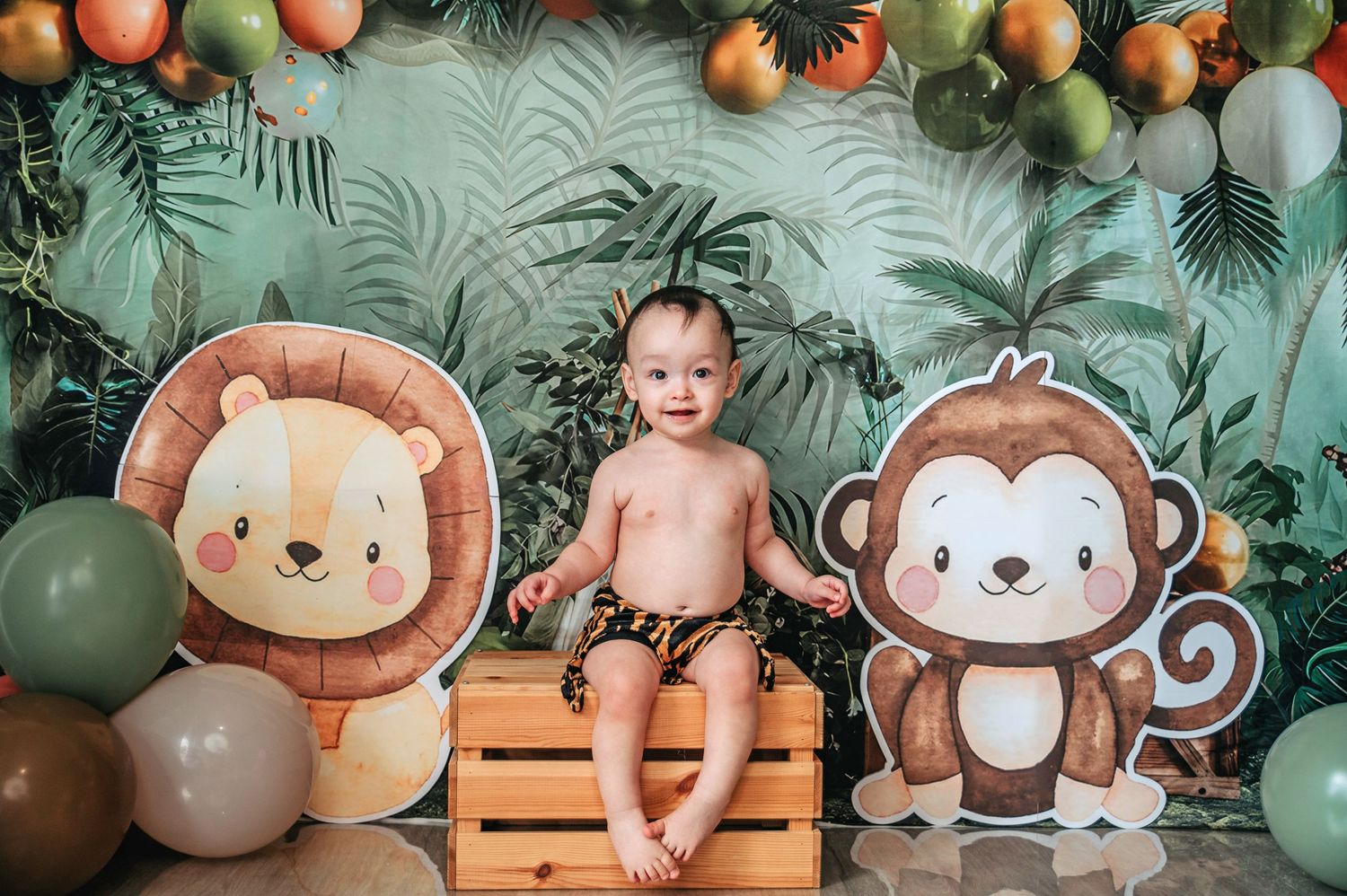 Jungle safari themed photoshoot with wooden crate, balloon decorations and animal cutouts.