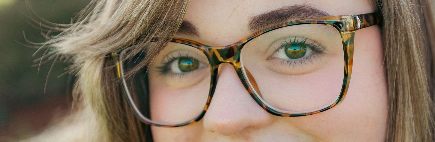 Close-up shot of tortoise shell glasses frames on person with green eyes.