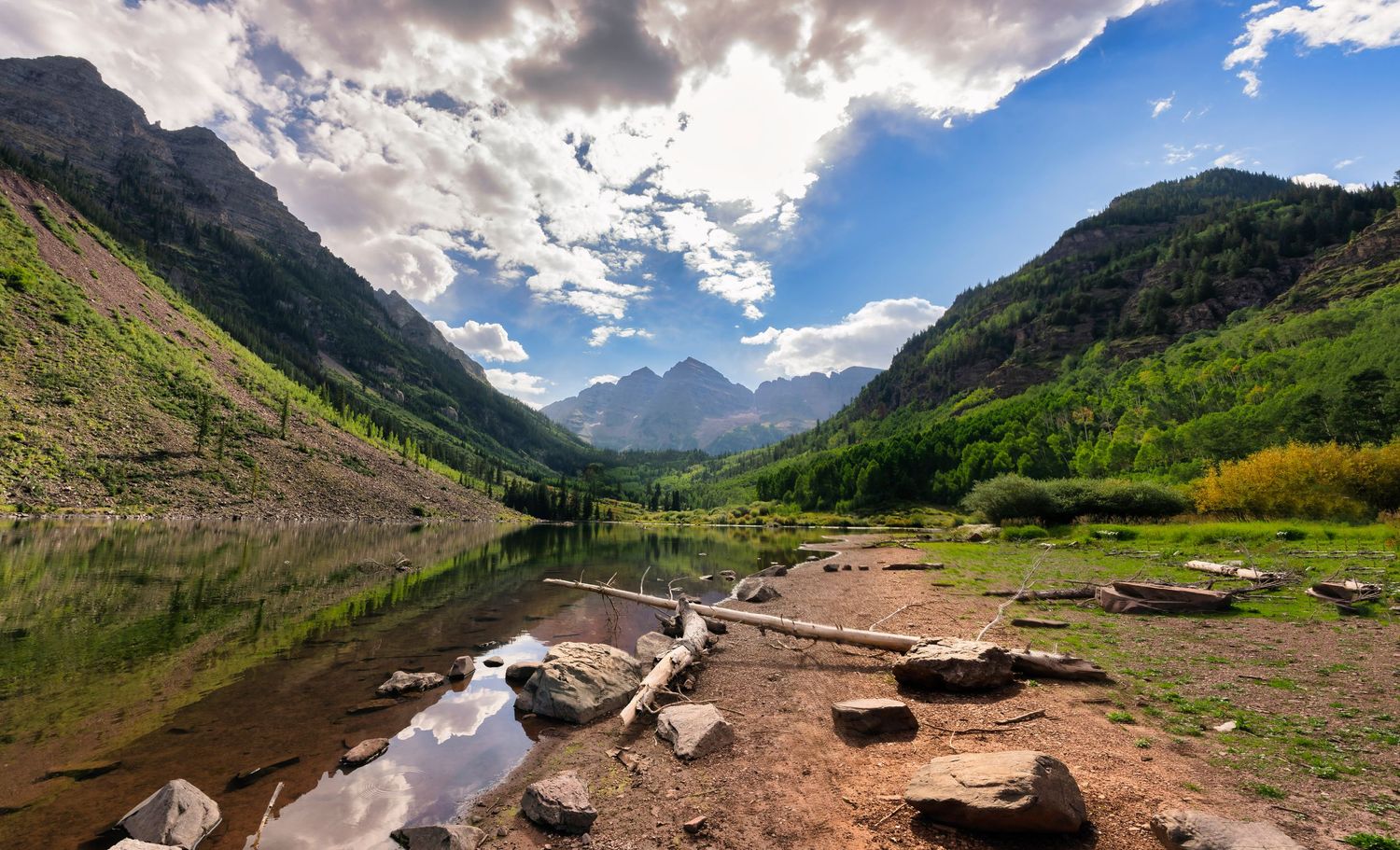 Dramatic mountain lake landscape with rocky shore and cloudy skies in late afternoon light.