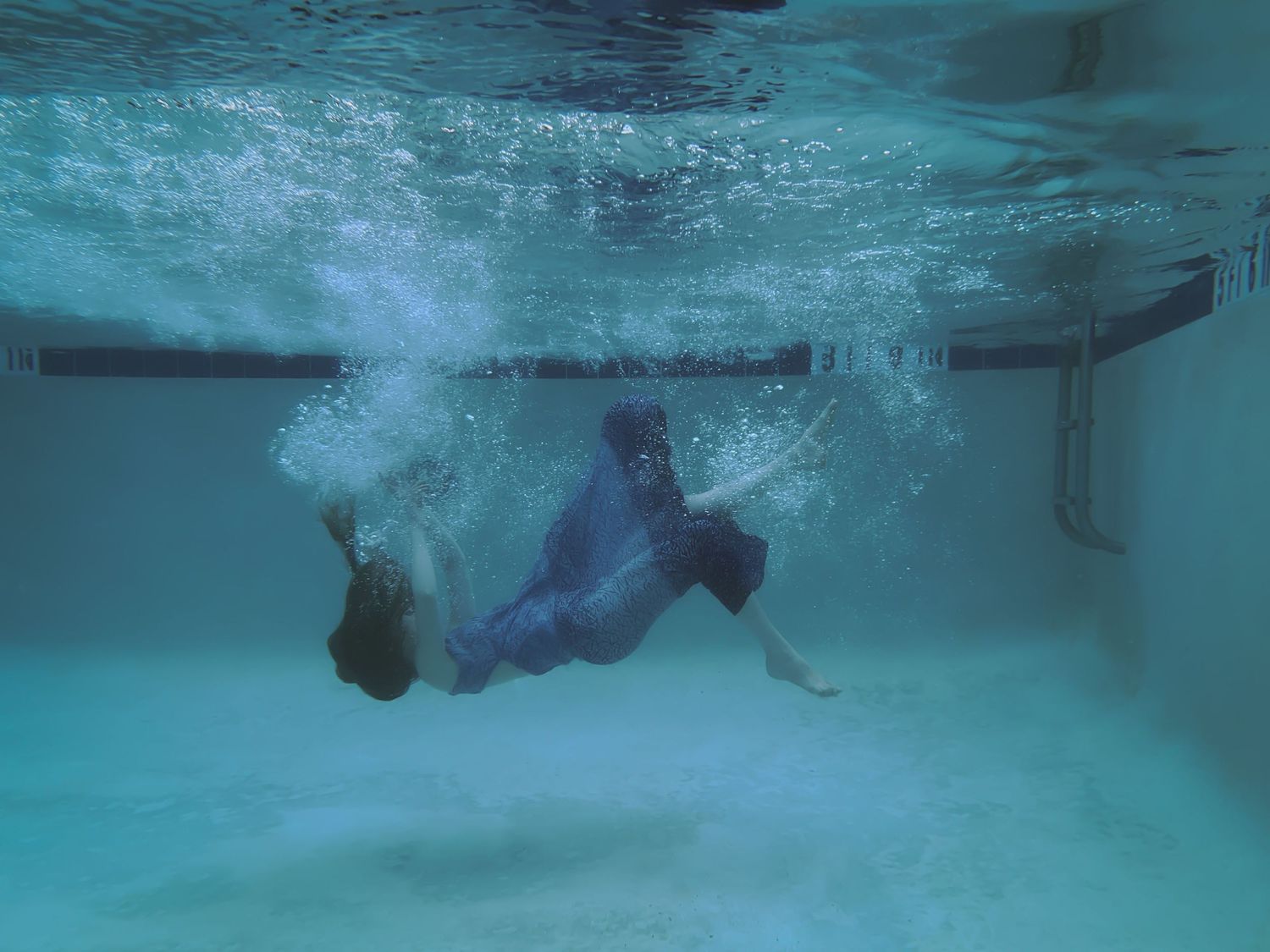 A woman in a blue dress falling into a pool