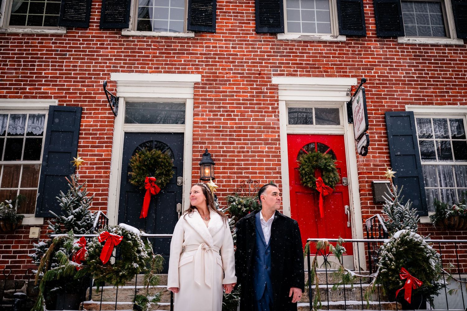 A brick house decorated for Christmas with wreaths and red bows on the windows and doors.