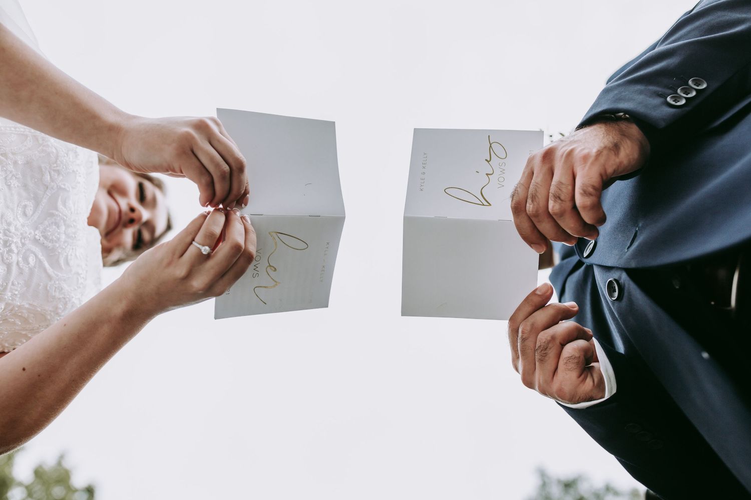Hands holding torn pieces of paper with writing against a bright sky.