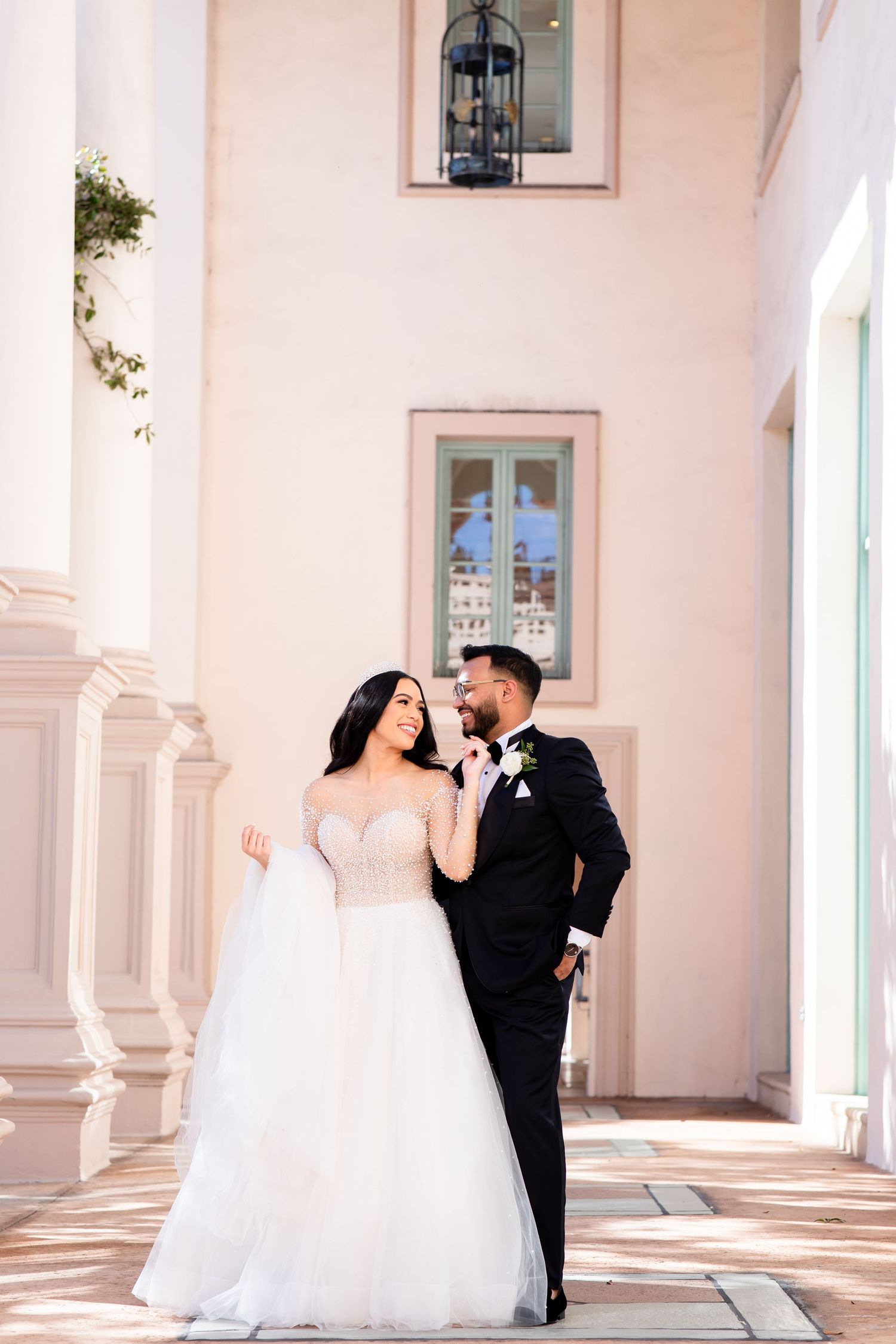 Romantic moment captured in an elegant colonnade with peach-colored walls.