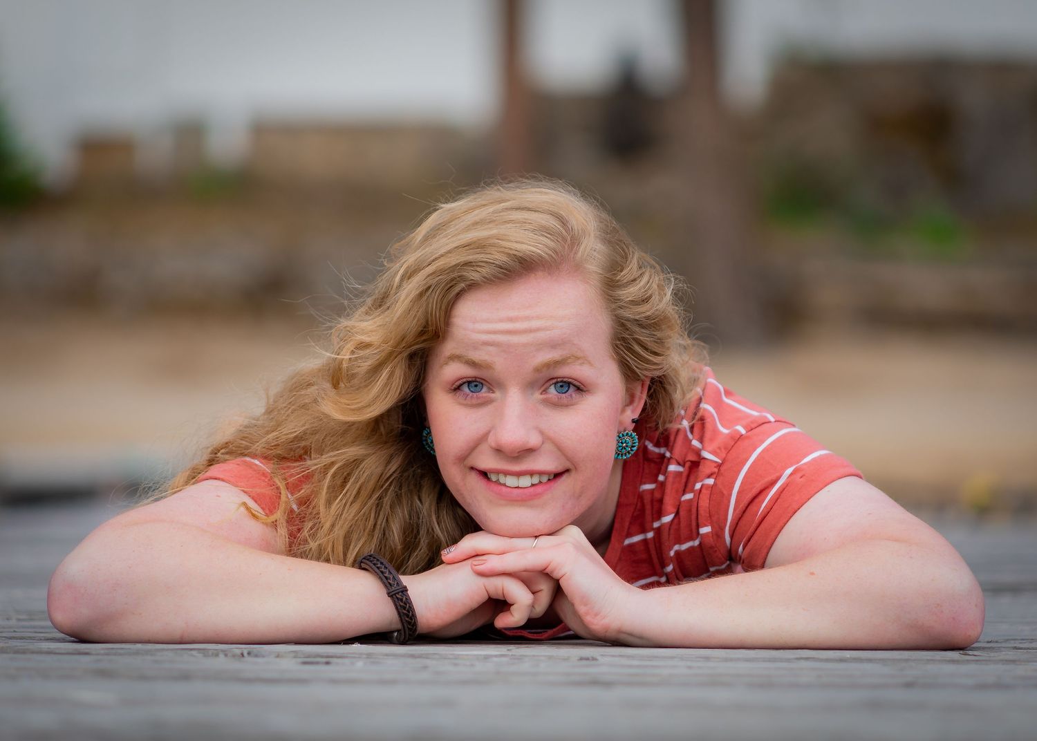 Portrait of someone resting on wooden deck with cheerful expression.