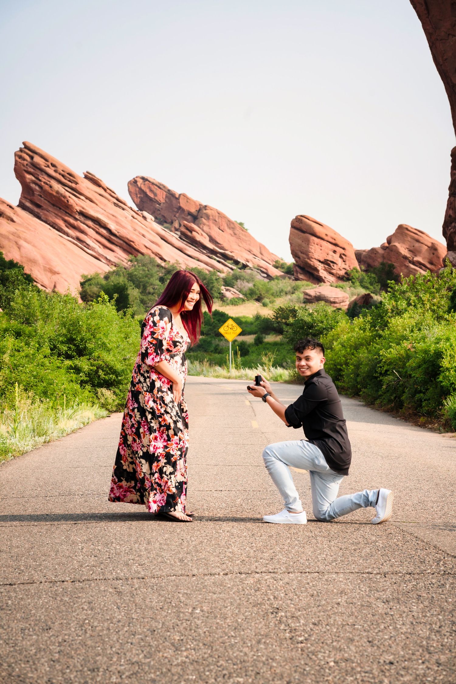 A marriage proposal scene at Red Rocks Park with dramatic red rock formations in the background.
