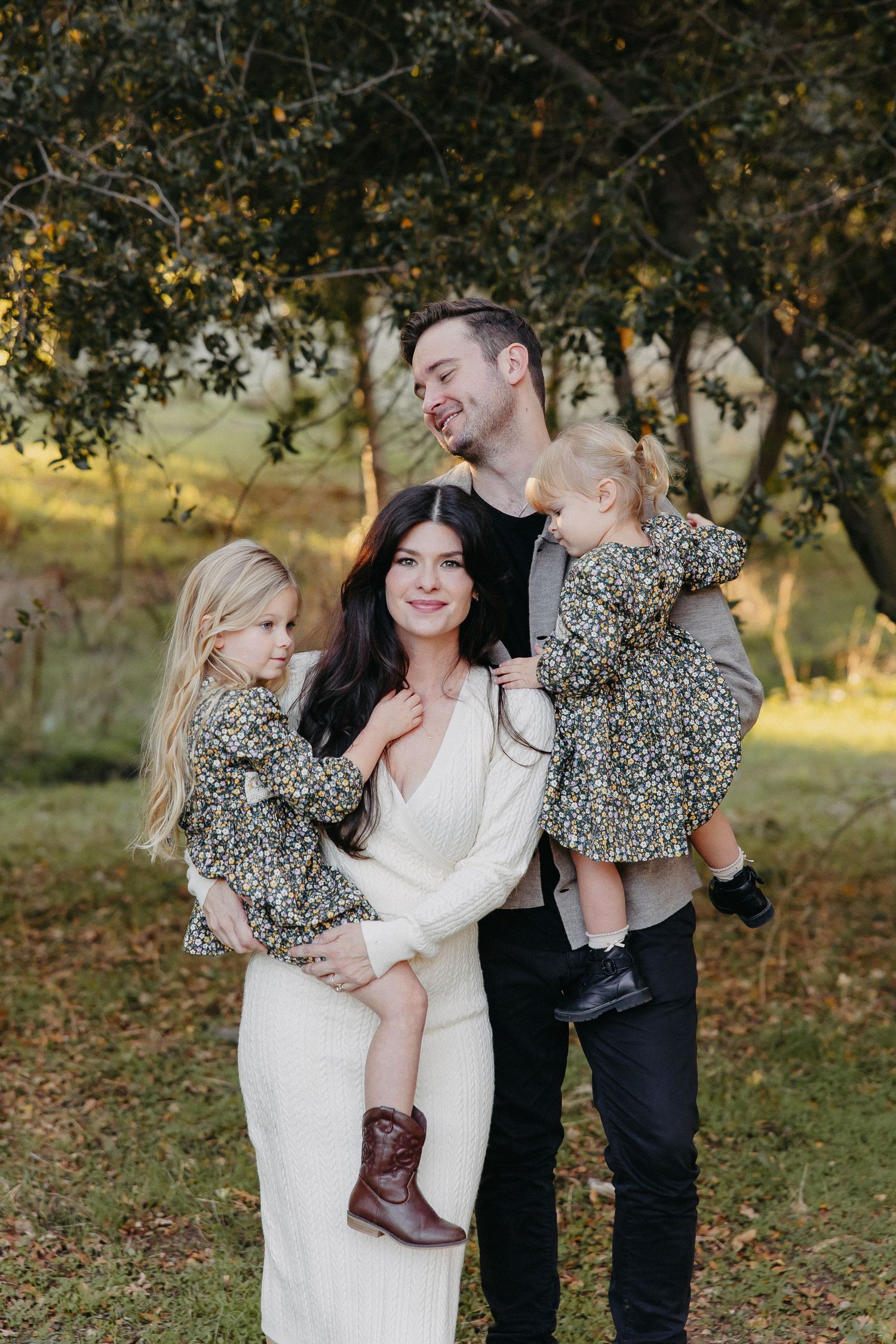 Family of four sharing candid laughs during autumn outdoor photoshoot in coordinated outfits.