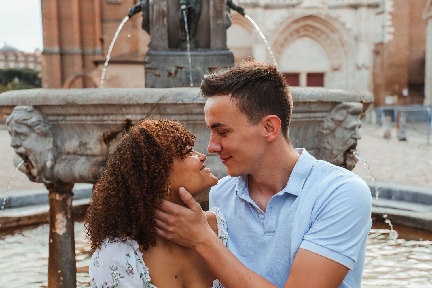 Romantic couple sharing intimate moment by historic fountain.