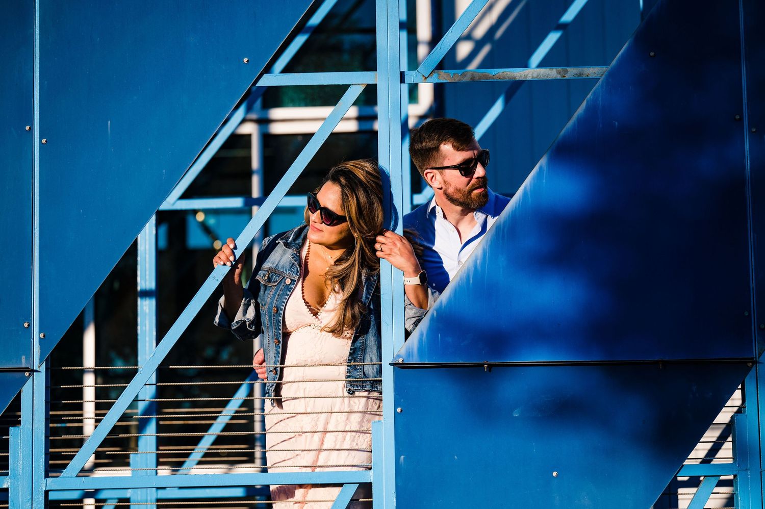 Two people standing on blue bleachers in bright sunlight.