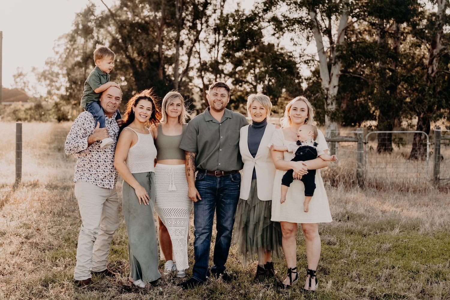 Group portrait of family members standing together outdoors at sunset.