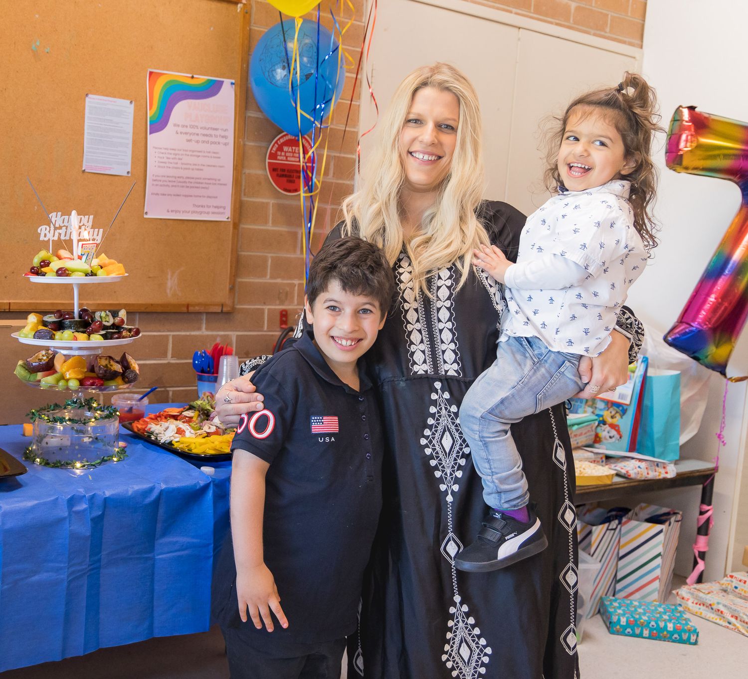 A party scene with balloons, cake, and decorations on a blue table.