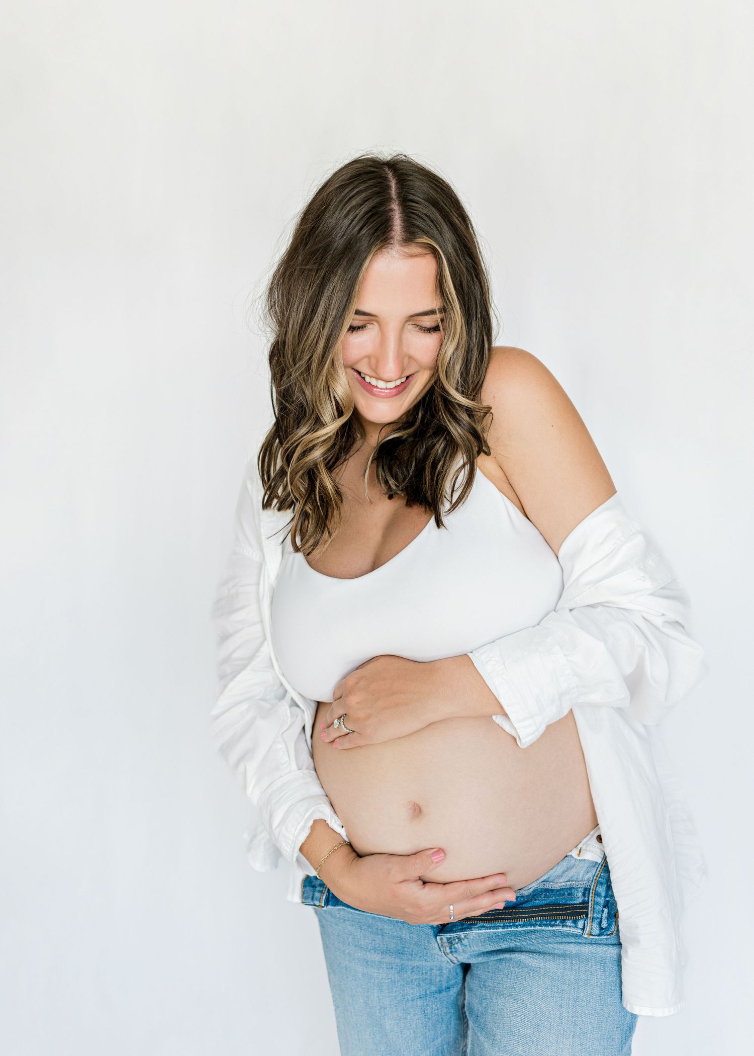 pregnant mom-to-be hugging her baby bump as she is looking down and smiling.