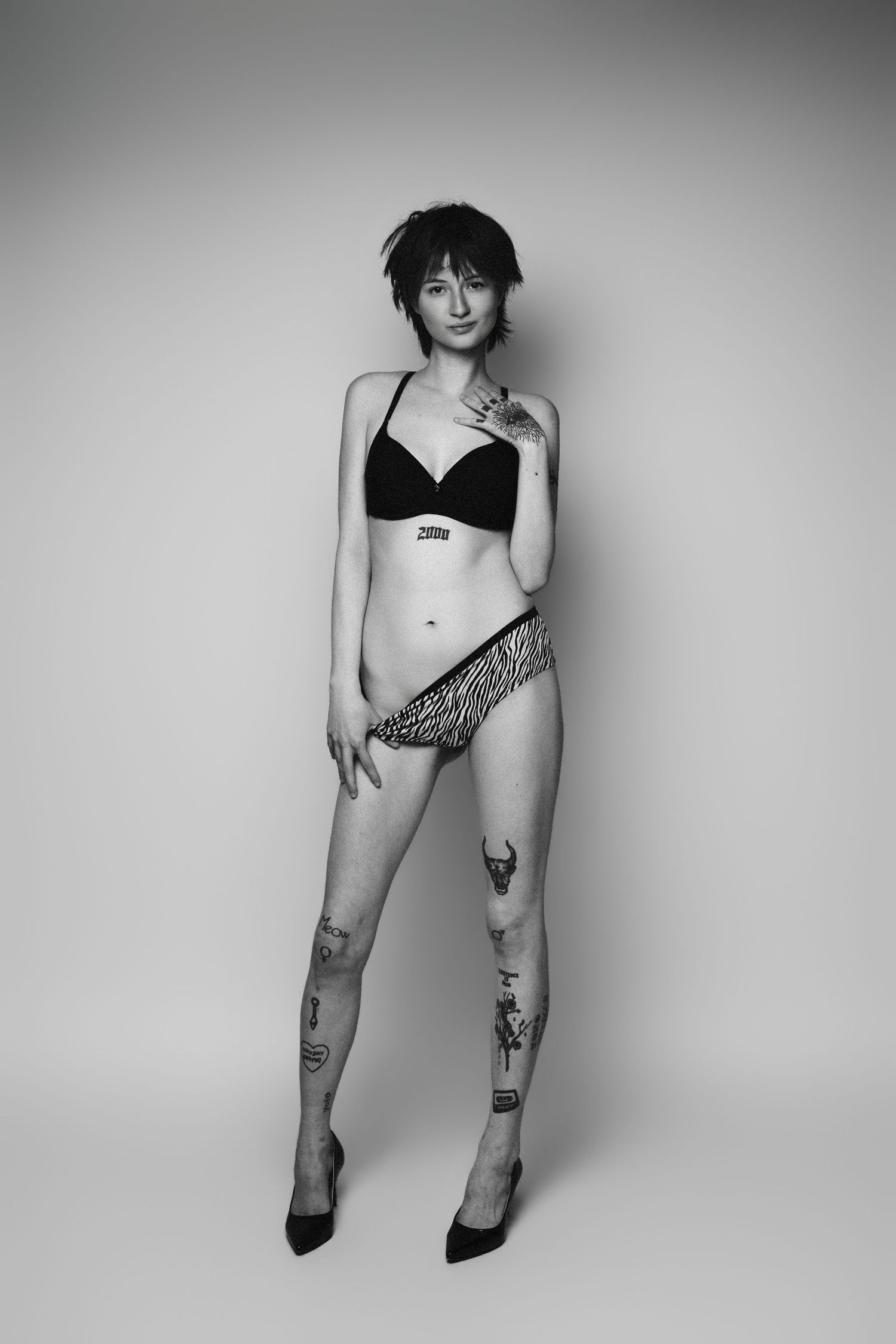 Person in black top and grey shorts lying on a grey floor in artistic boudoir pose.