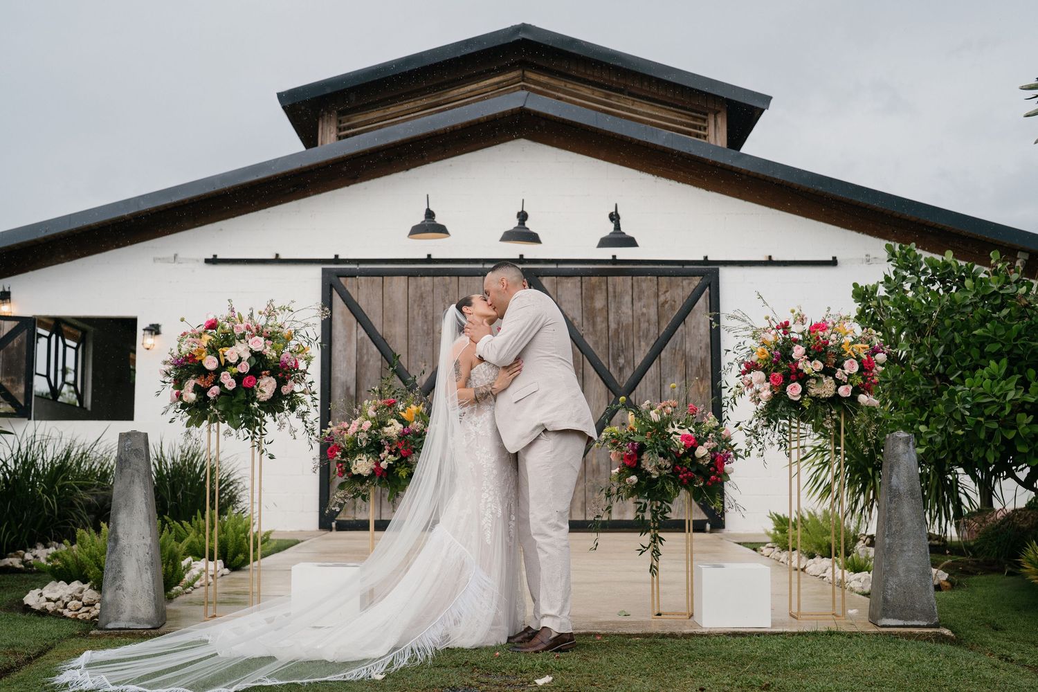 Couple celebrates joyfully during their rustic barn wedding reception with guests watching in the background.