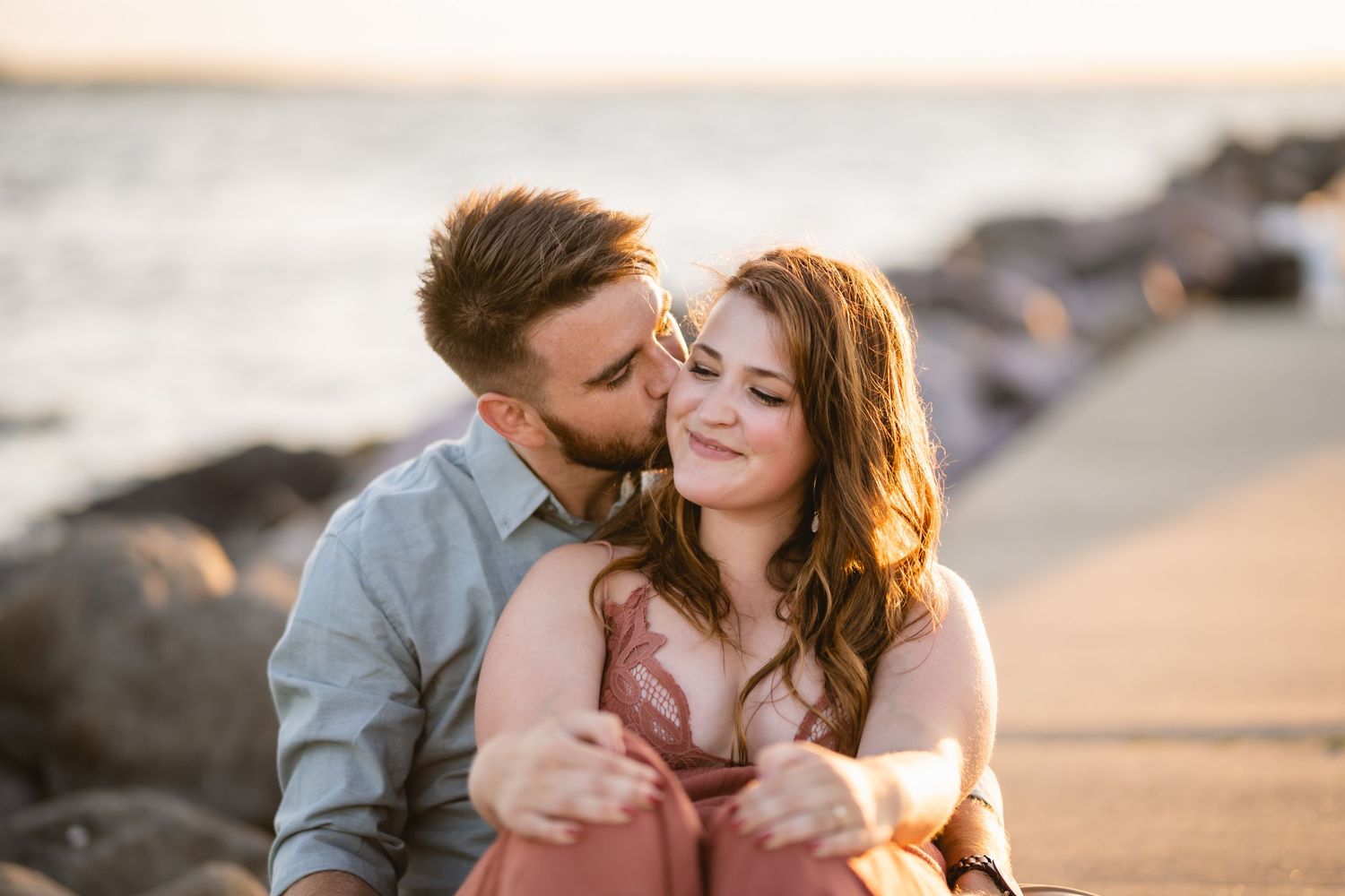 A couple cuddling and giving a kiss on a sidewalk
