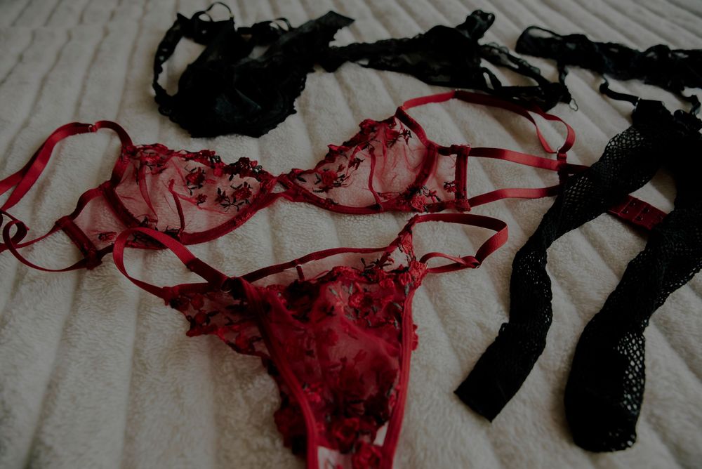 Red and black lace lingerie sets laid flat on a white surface.