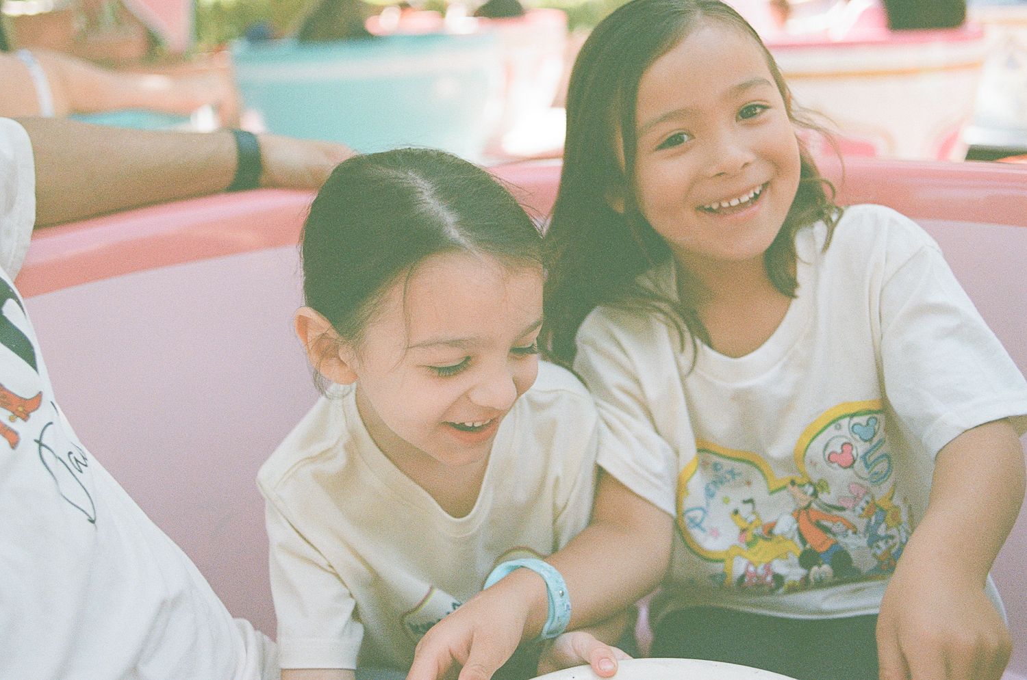 Two young girls smiling and laughing together on a Disneyland tea cup ride.