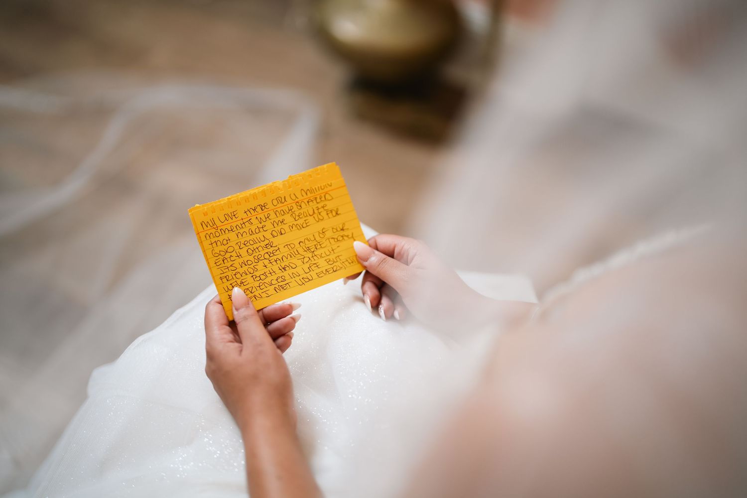 Bride in white dress reading a handwritten note on yellow paper, a heartfelt wedding day letter.