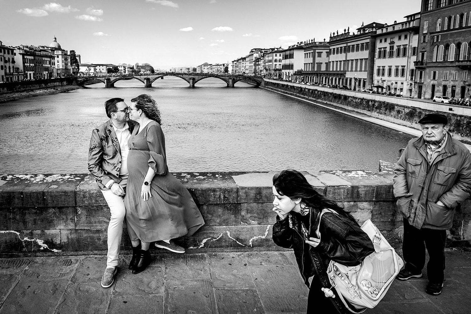 Zwart-wit zwangerschapsshoot Florence – koppel zittend op brug over de Arno met voorbijgangers