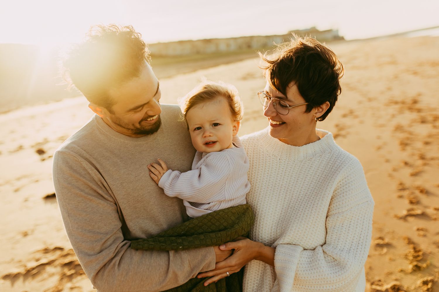 A family of three standing on the beach during an outdoor family photography session in Whitstable.