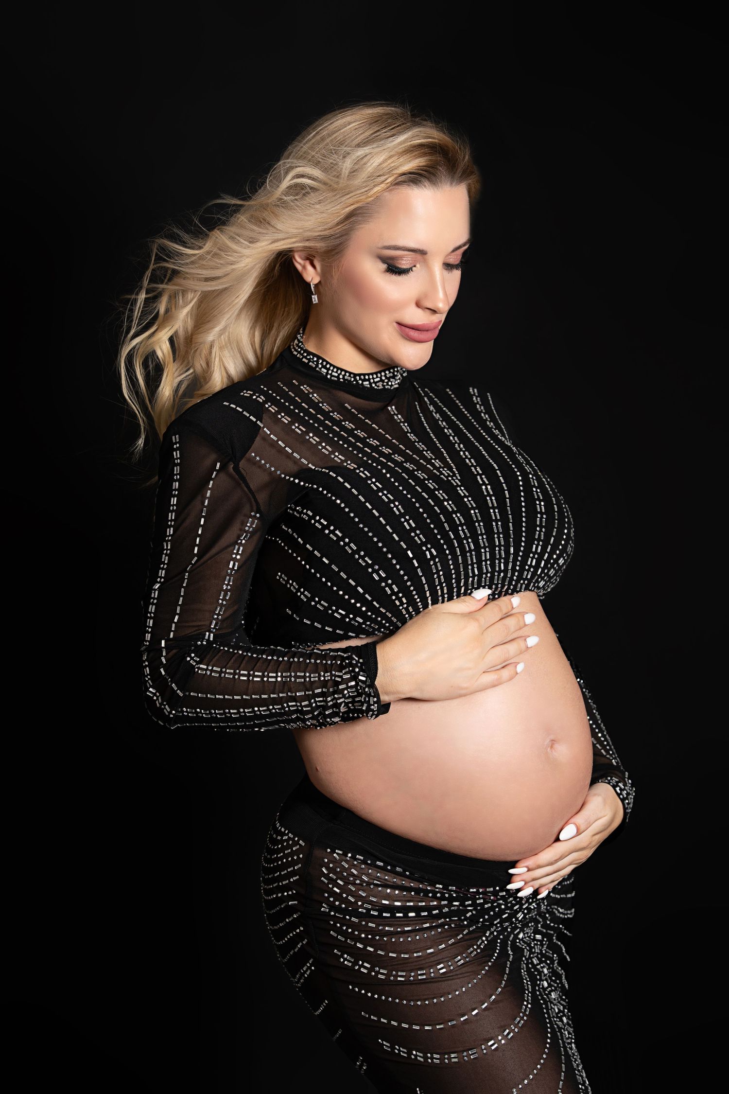 Luxury maternity photography Dubai editorial maternity photoshoot with a pregnant woman in a flowing gown captured in a professional studio.