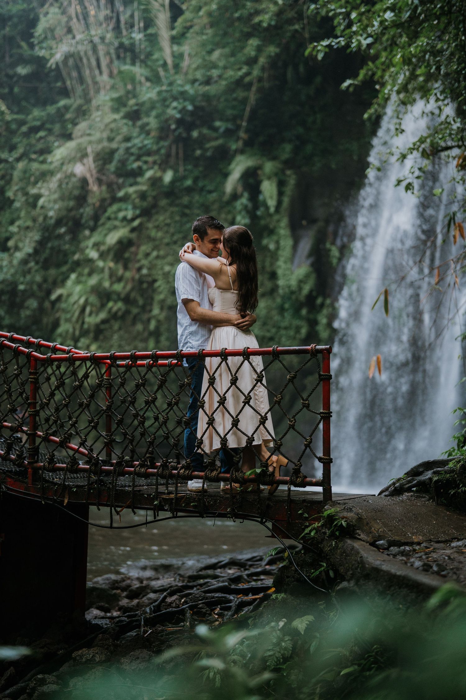 Couple walking along a green garden pathway surrounded by tropical plants.