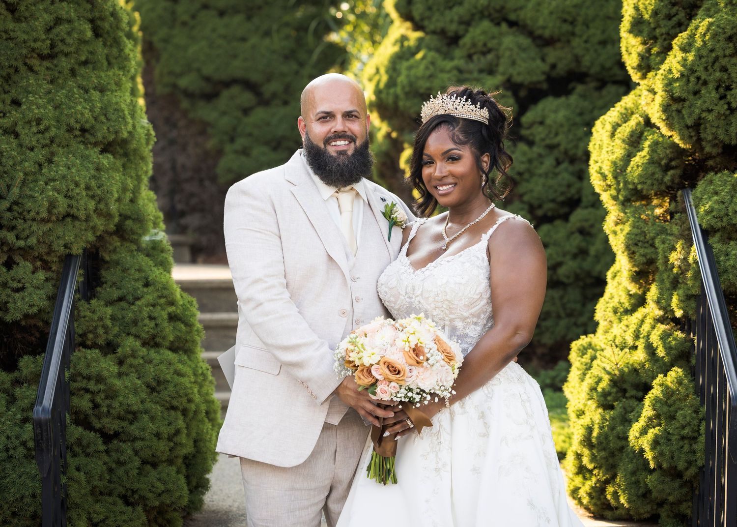 Newlyweds share an intimate moment outdoors with autumn foliage and rustic architecture in background.