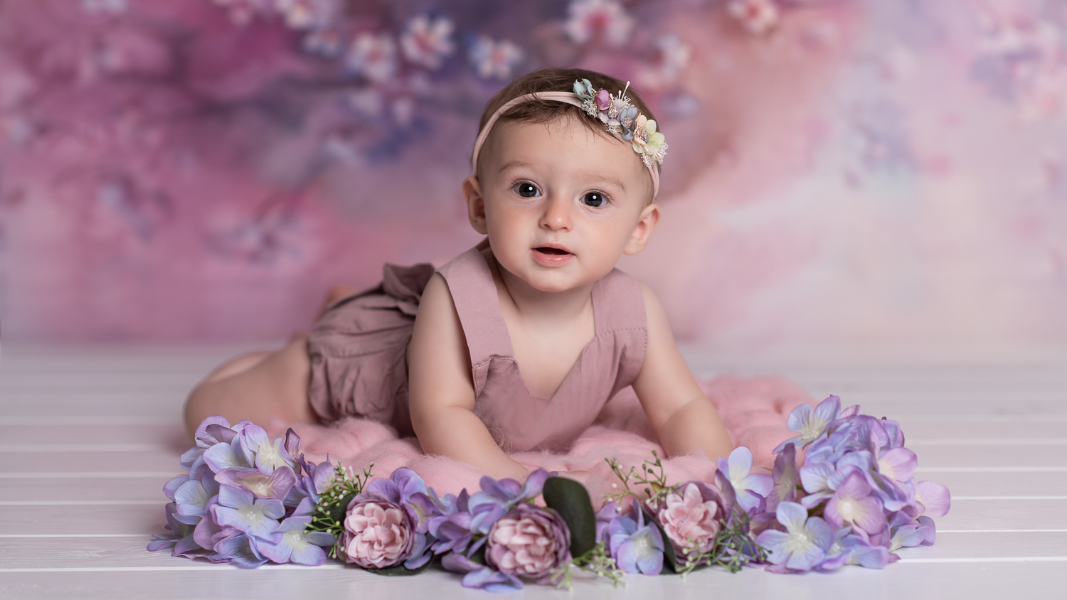 bebè su un set di fiori viola e rosa