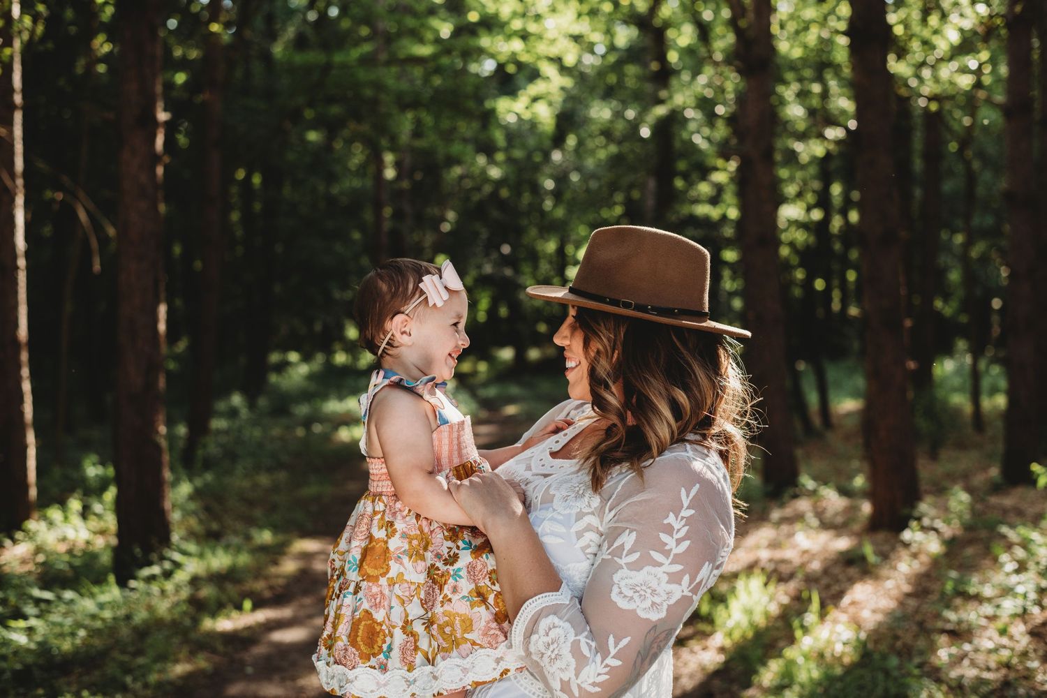 A touching moment between parent and child in a sunlit forest setting.