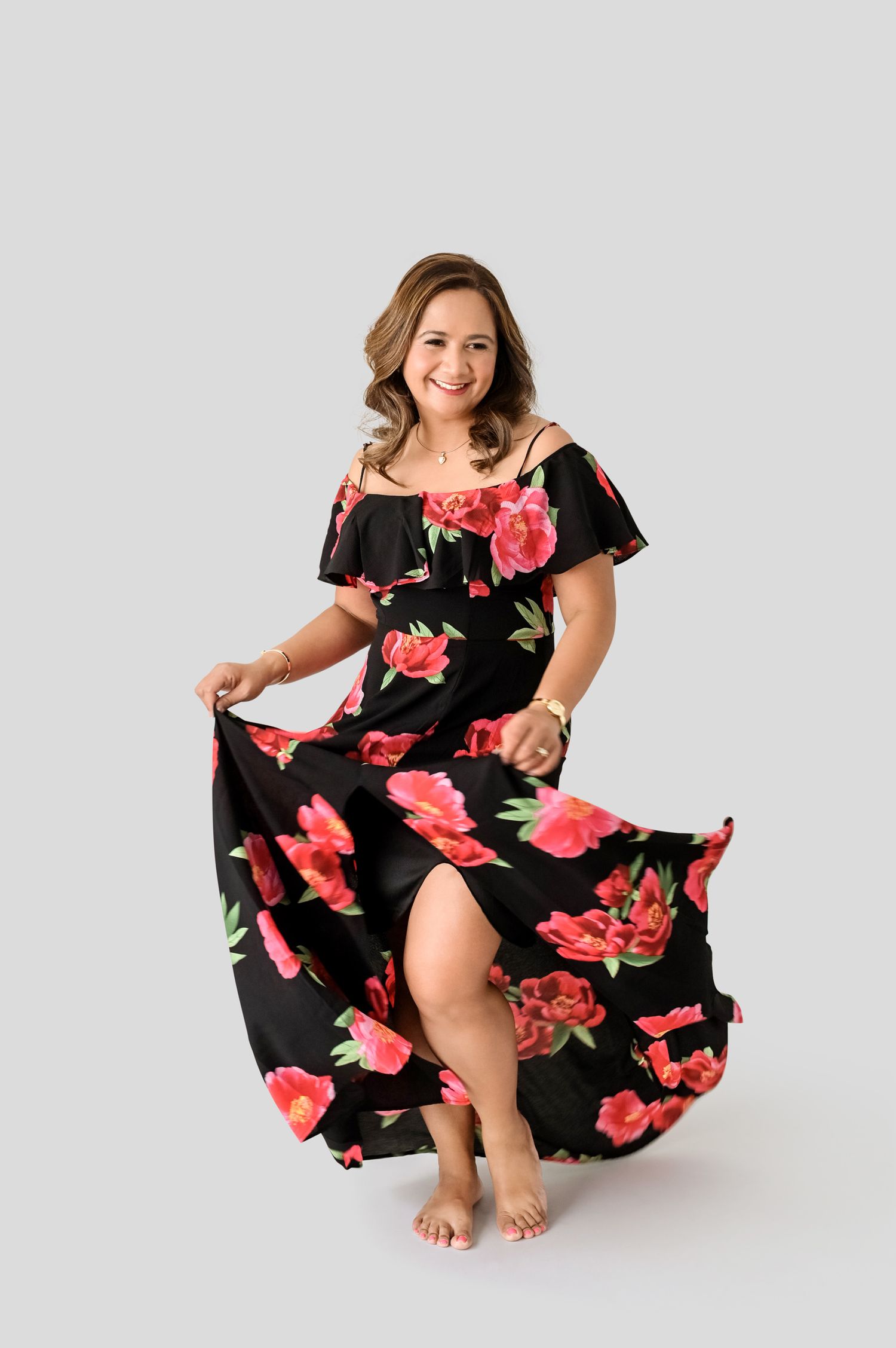 Dancing in a flowing black floral dress with pink roses against light background.