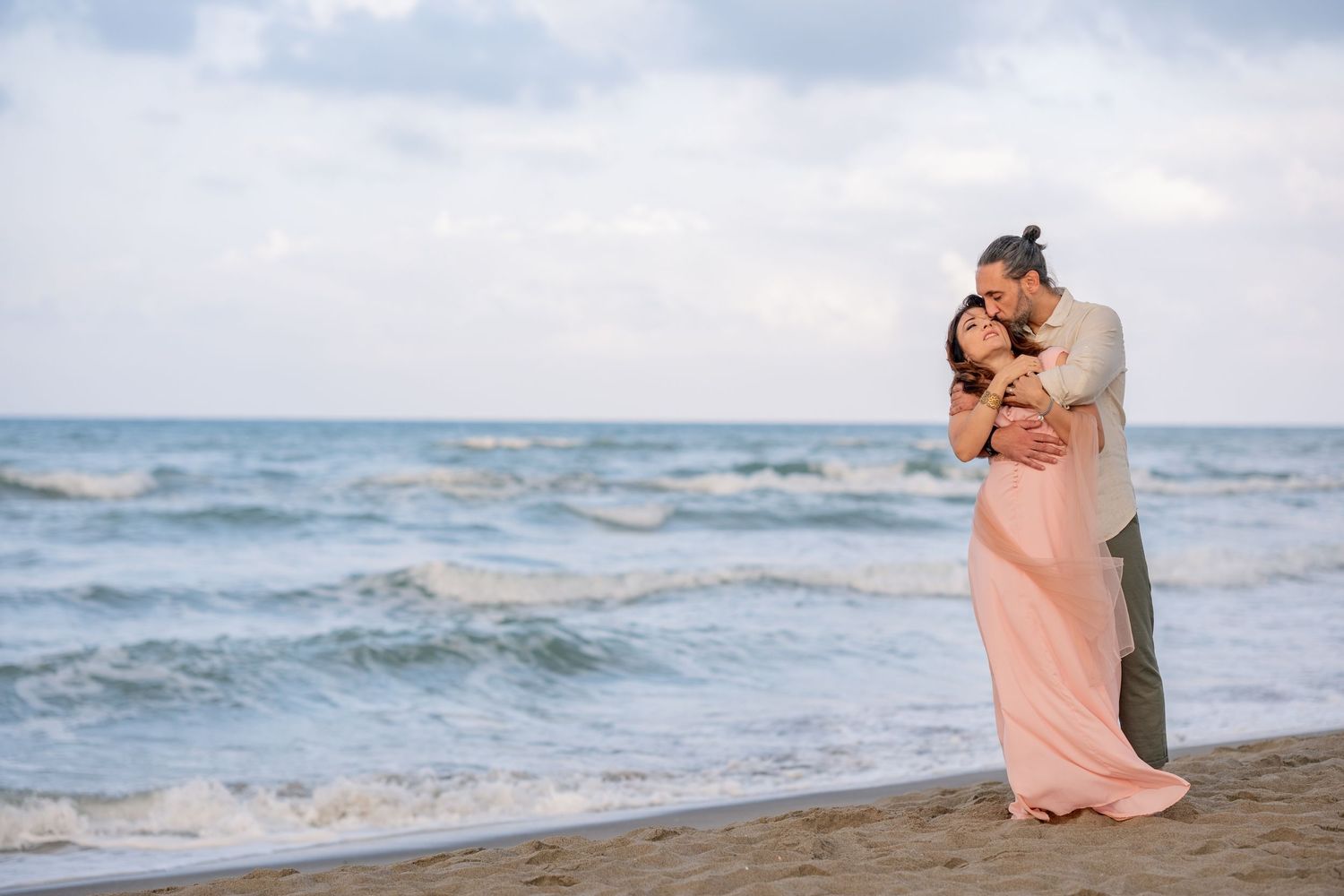 Romantic beachside embrace with waves crashing in the background.
