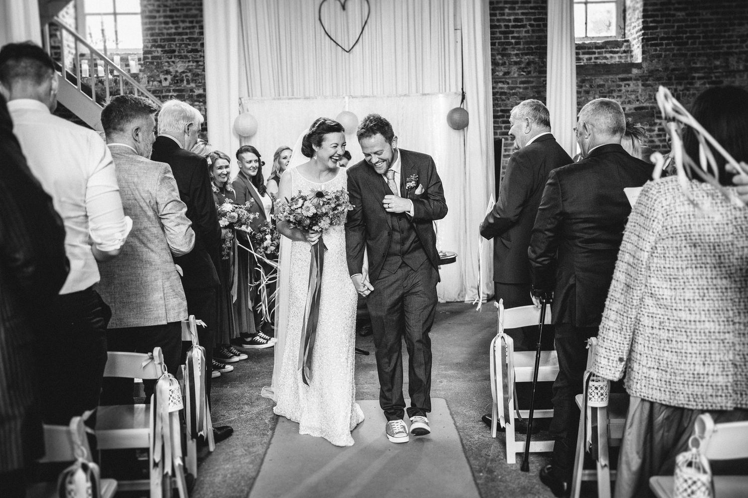 A joyful wedding ceremony moment as the newlyweds walk down the aisle while guests look on.