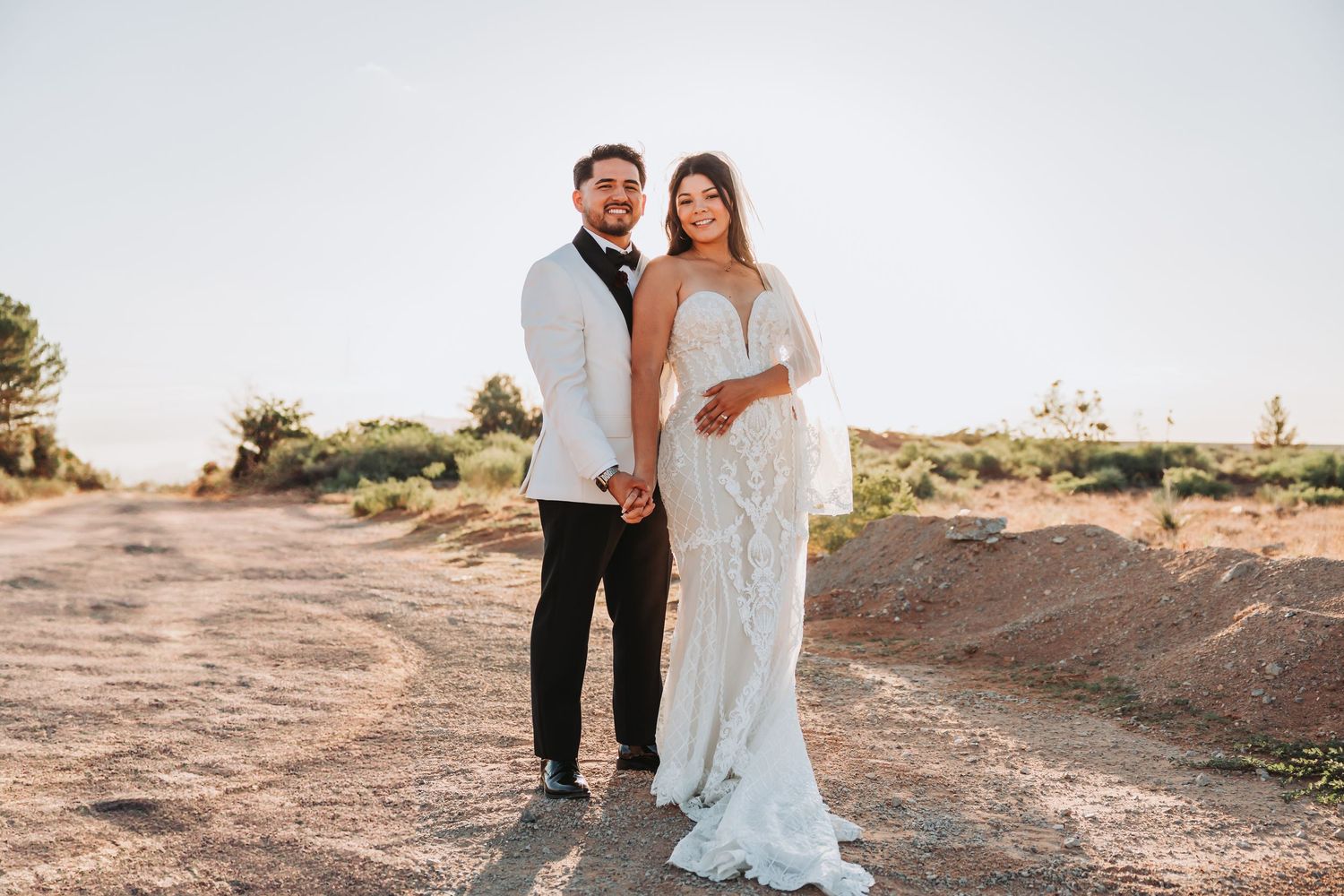 A romantic sunset desert portrait session captures couple in formal attire sharing tender moments in golden light.