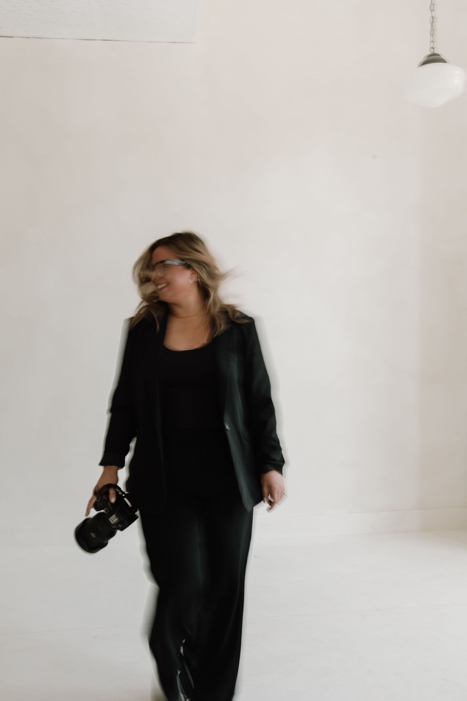 A series of motion blur photographs showing a person in black clothing moving against a white wall.