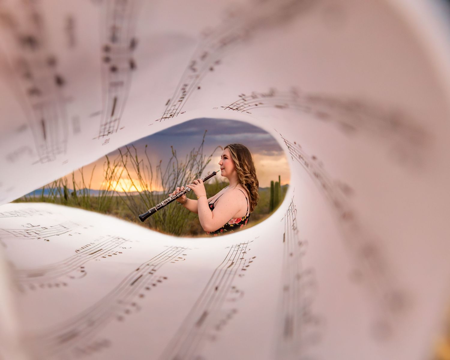 Desert senior session playing oboe through music sheets during monsoon sunset – Tucson senior pictures, Arizona Senior Photographer