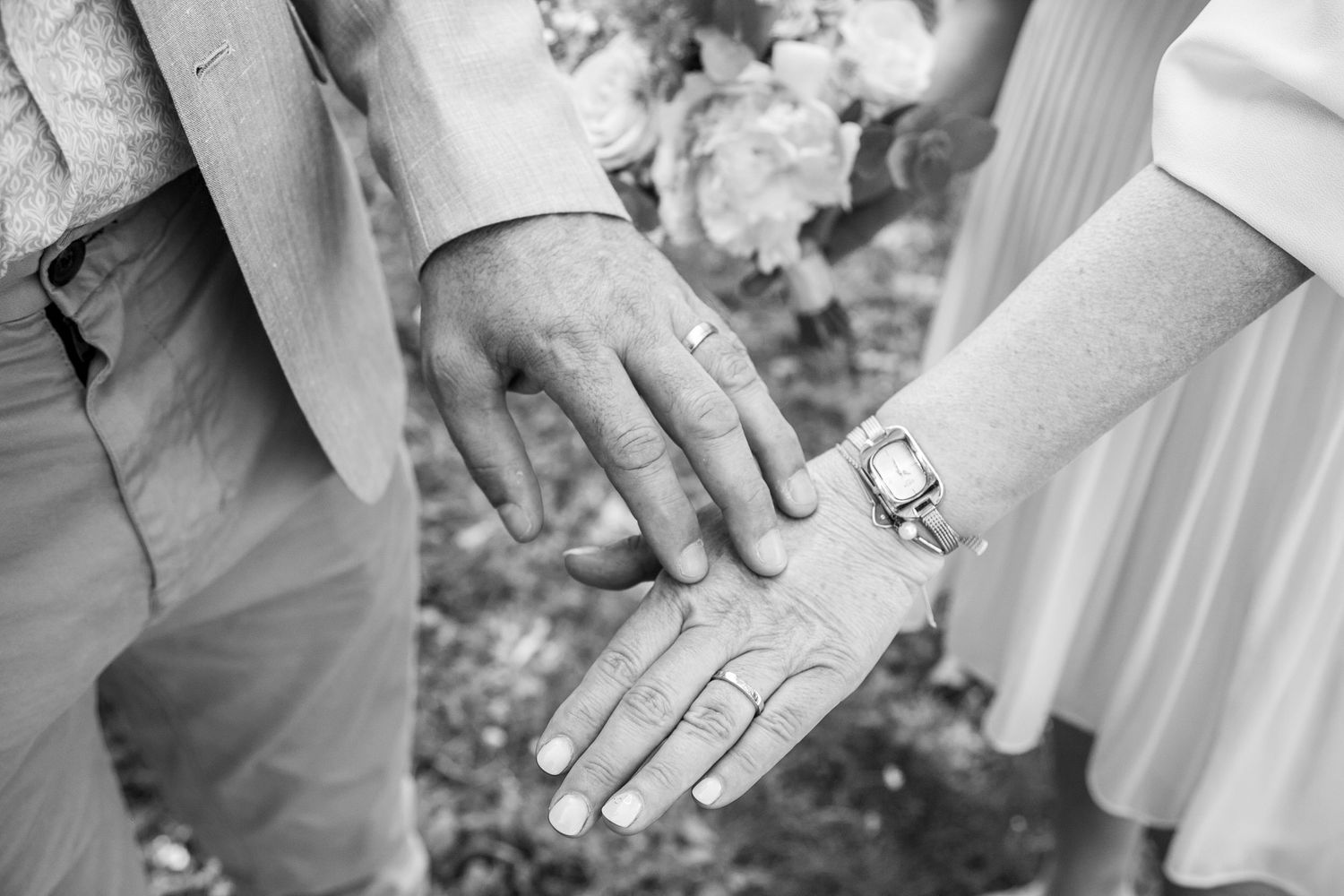 Photographie à sauvegarder précieusement : des mains d'un homme et d'une femme qui s'effleurent tendrement. Ils portent chacun une alliance.
