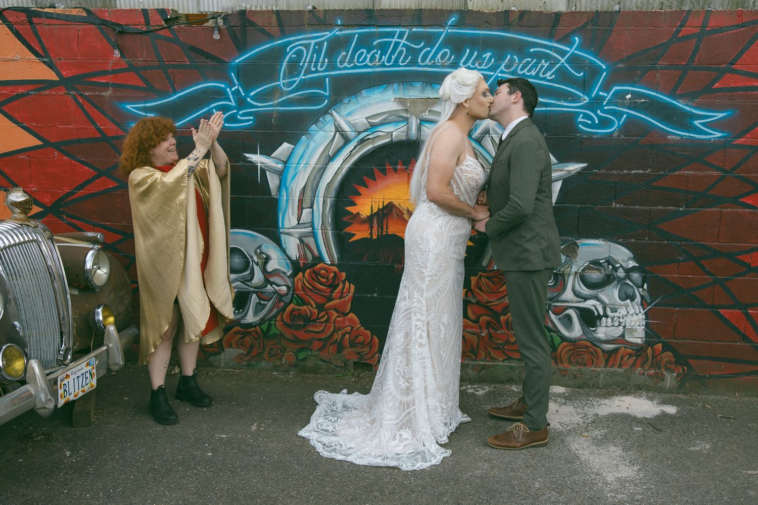 gay couple kissing during wedding ceremony with officiant clapping