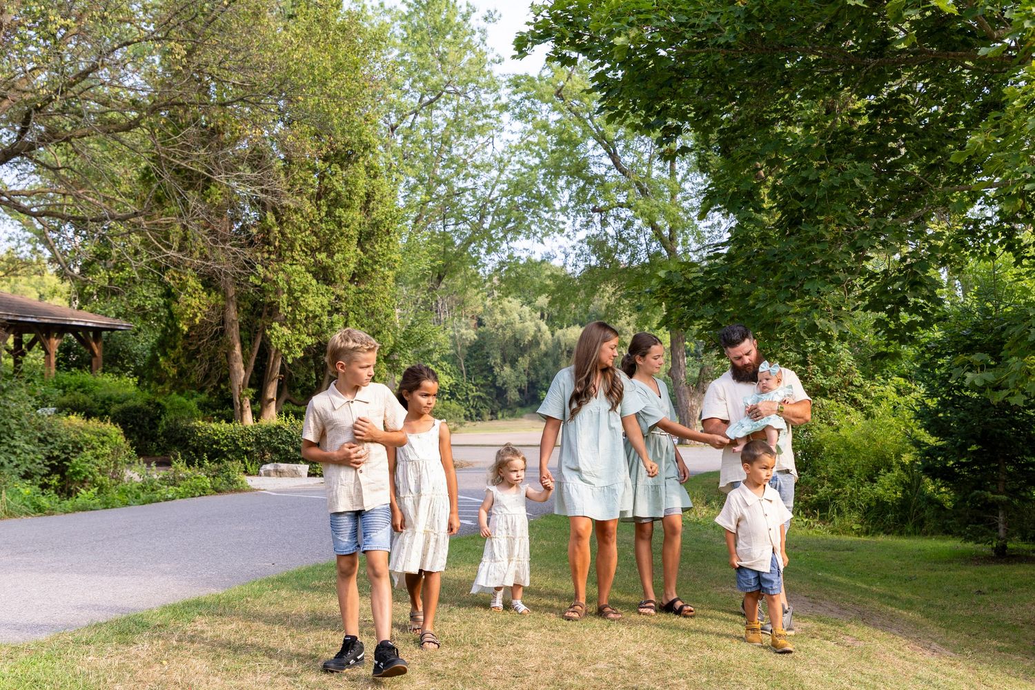 A family of 8 walking through a park on a beautiful late summer evening