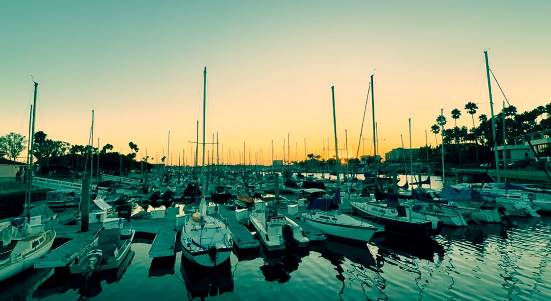 Five panoramic views of boats moored in a marina during sunset with masts silhouetted against a golden sky.