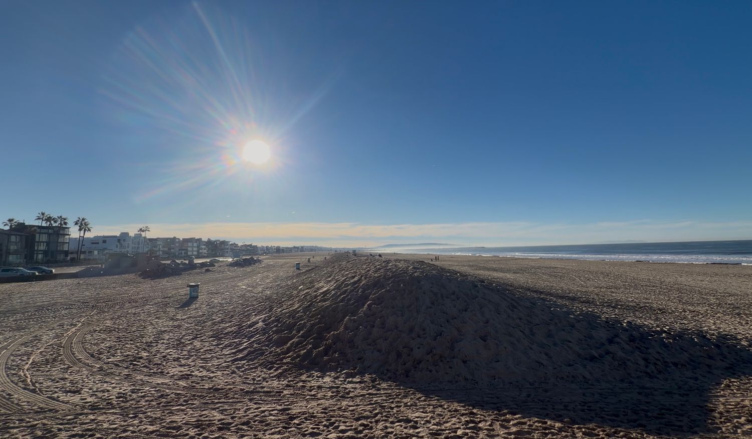 Panoramic view of a vast desert landscape under bright sunlight with dramatic shadows stretching across the barren terrain.