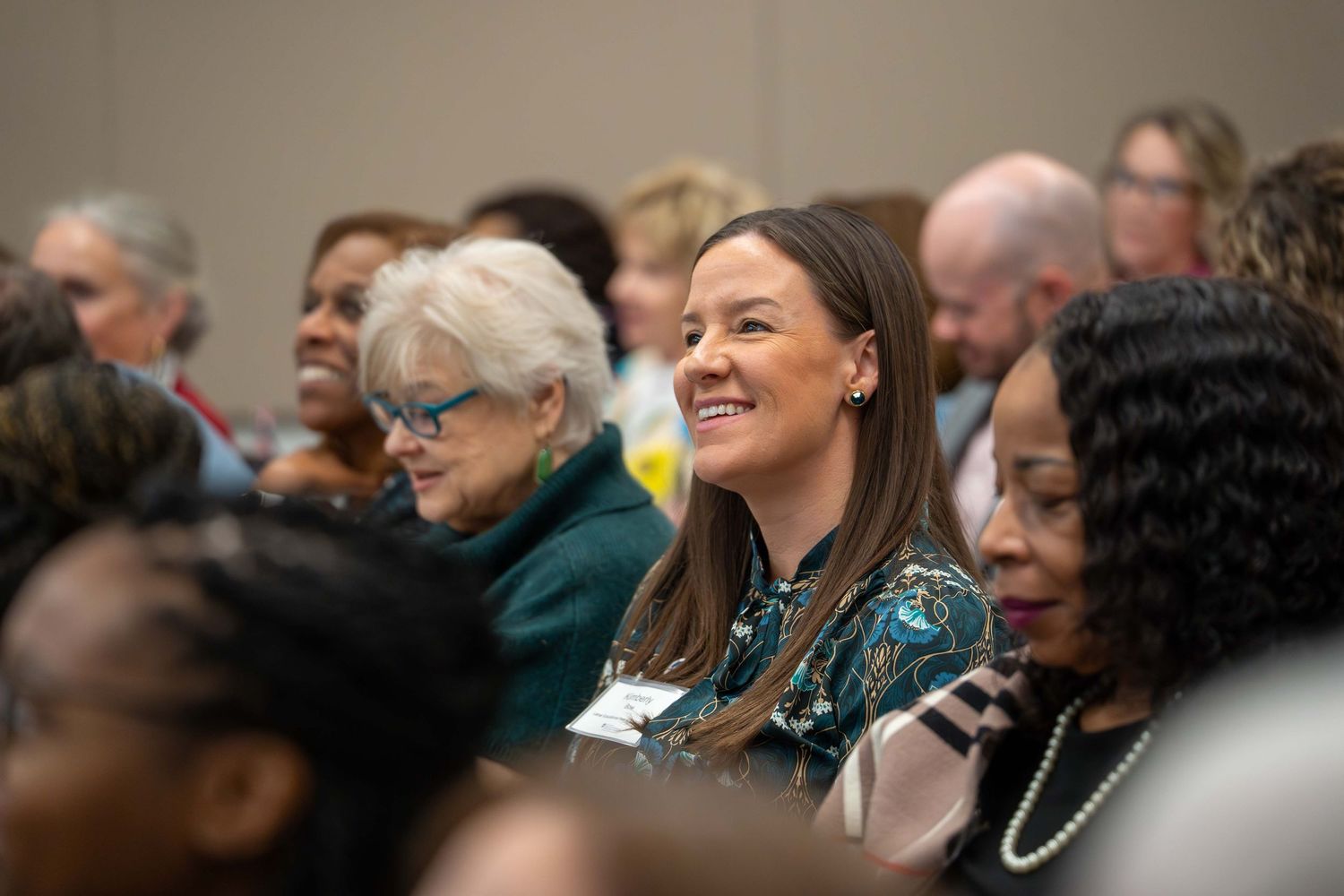 Audience members laughing and smiling during an indoor event.