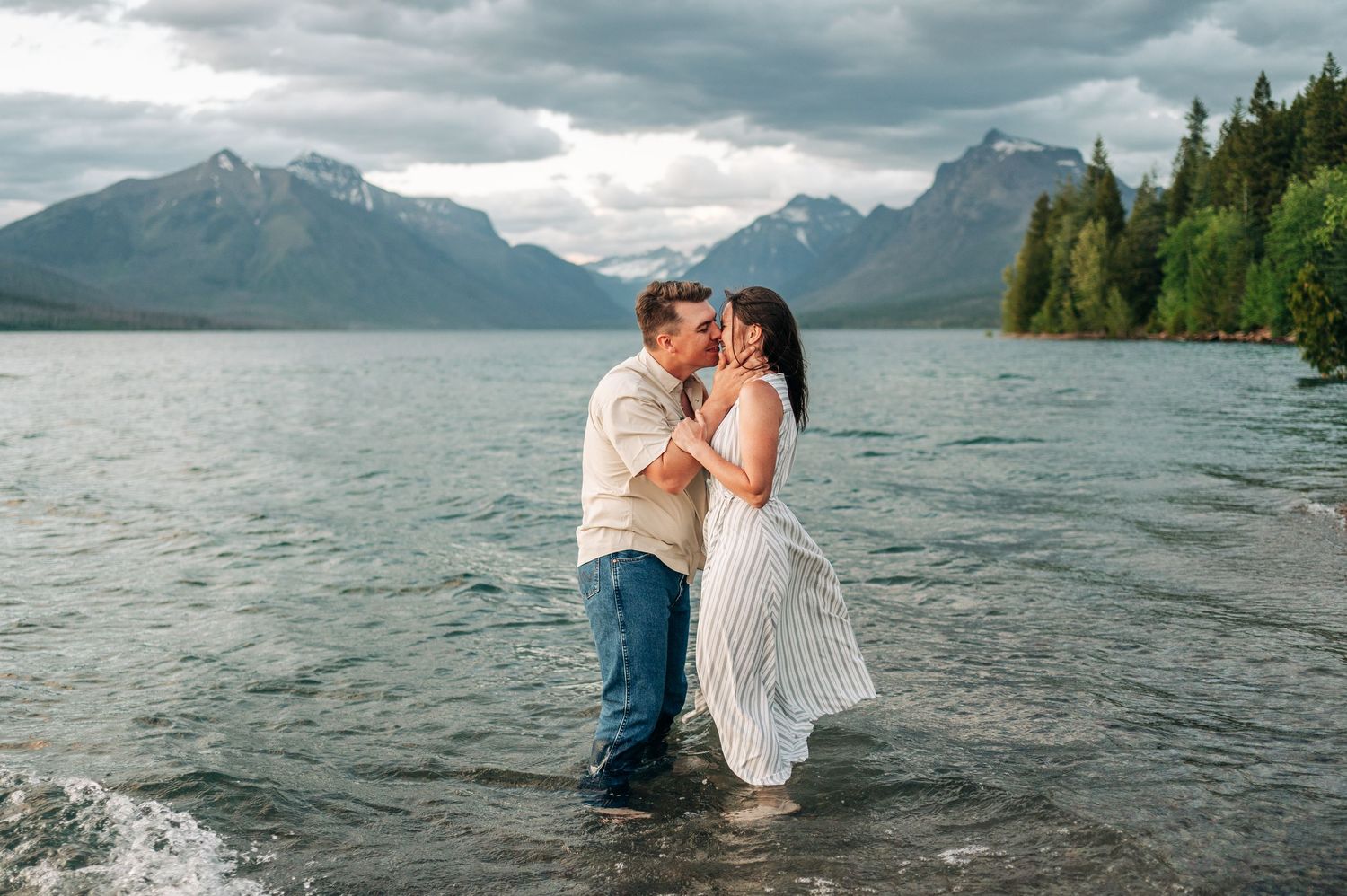 A marriage proposal sequence on a scenic lakeside beach with mountains in the background.