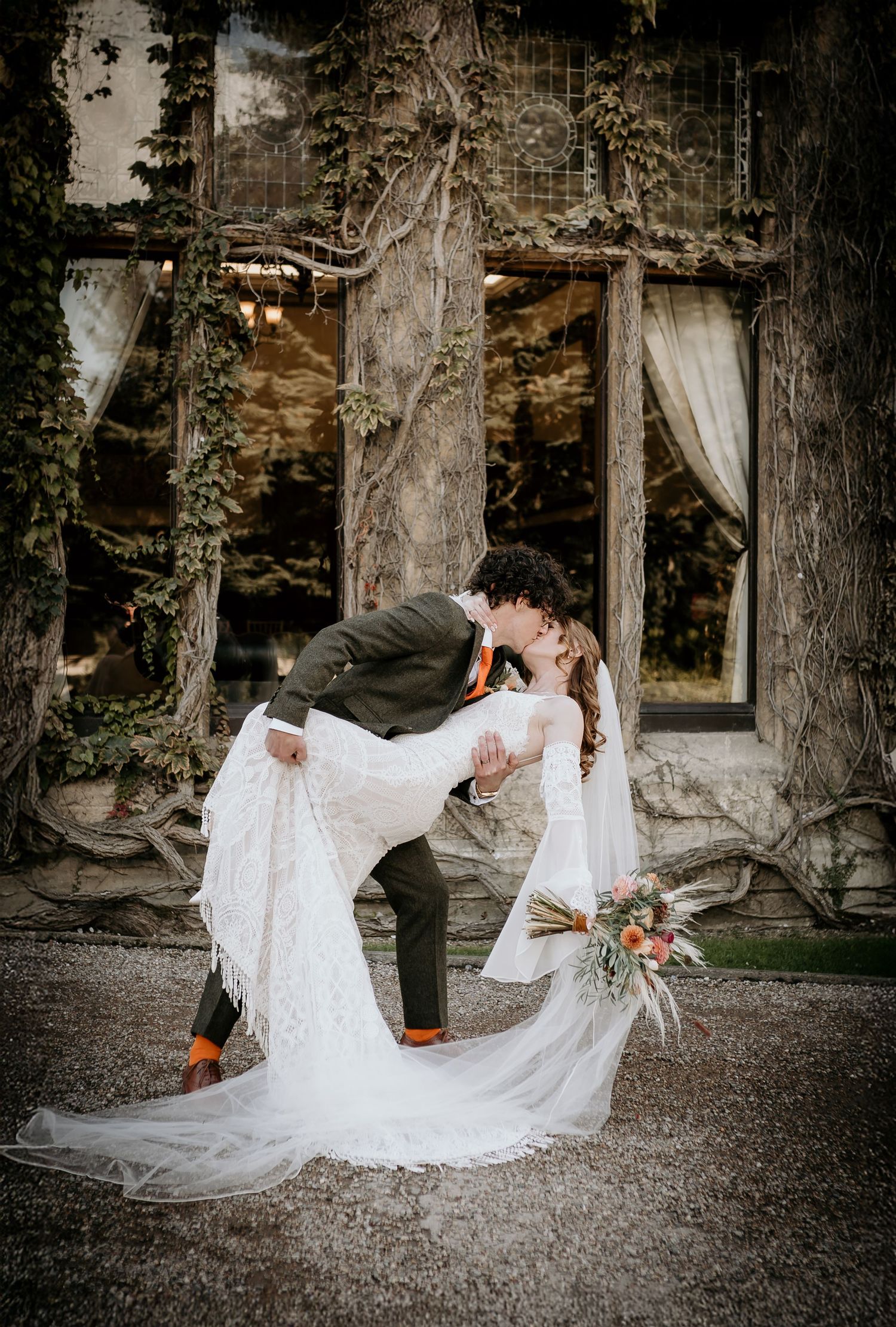 A couple shares romantic moments in formal attire while celebrating their wedding day at a rustic stone venue.