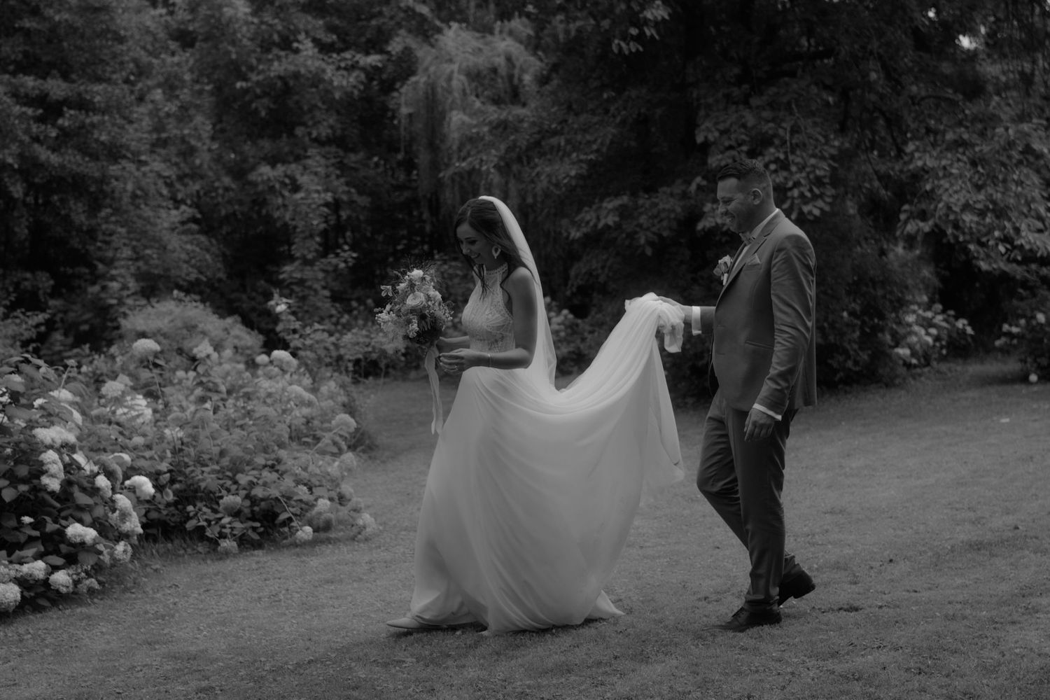 Black and white outdoor wedding photography session in a garden setting.