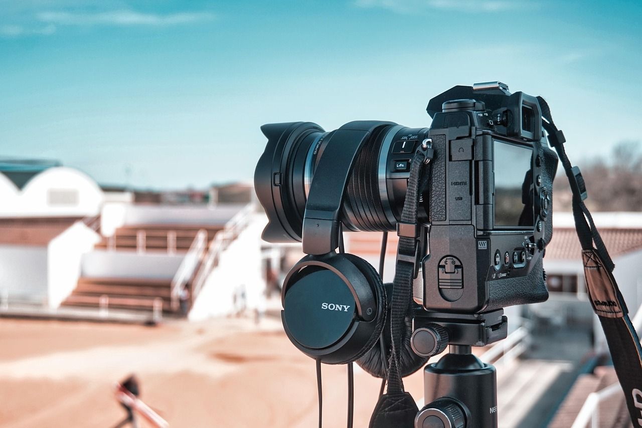 Professional DSLR camera with wide angle lens mounted on tripod against blurred outdoor background.