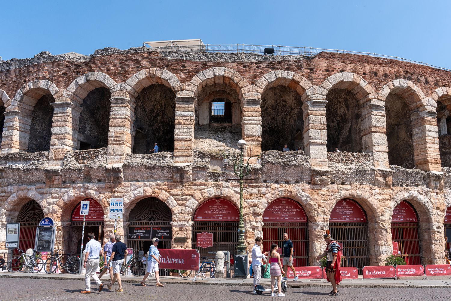 Ancient Roman arena with arched architecture and red awnings in Verona, Italy.
