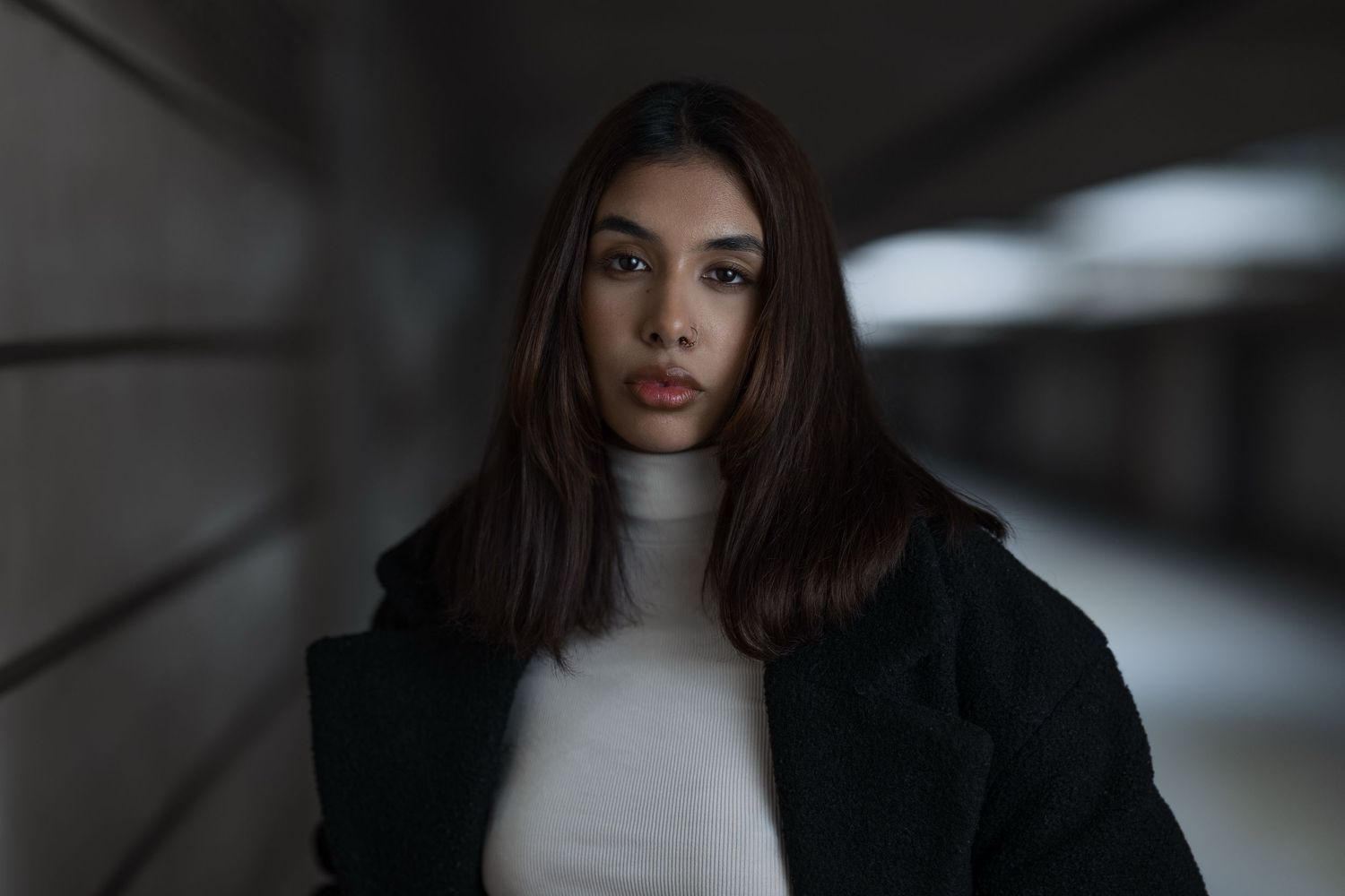 Dark fashion portrait series showing model in black jacket and white turtleneck against moody lighting.